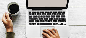 Wirtschaft und Management Gezeigt wird ein Laptop aus der Vogelperspektive. Links davon befindet sich eine Kaffeetasse.