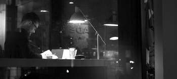 Bachelor Bildungswissenschaften Ein Mann sitz in einem dunklen Raum an einem Schreibtisch und liest in einem Buch. Er trägt eine Brille und hält einen Stift in der Hand. Auf seinen Schreibtisch scheint eine Schreibtischlampe. Im Hintergrund lassen sich weitere Lampen erahnen.