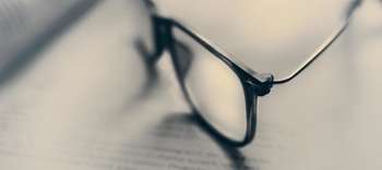 Rechtswissenschaften Das Bild zeigt eine Brille, die auf einem Buch abgelegt ist.