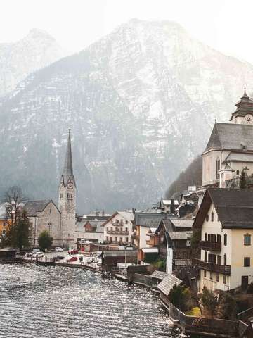 Ausschnitt einer Kleinstadt in Österreich direkt am Wasser gelegen. Im Hintergrund eine Berglandschaft.