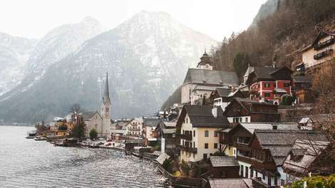 Ausschnitt einer Kleinstadt in Österreich direkt am Wasser gelegen. Im Hintergrund eine Berglandschaft.