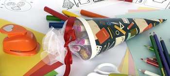 Bachelor Grundschullehramt Aufnahme einer gebastelten Schultüte auf einem Tisch liegend. Um die Tüte herum verschiedene Bastelmaterialien. Die Tüte ist mit Geschenken gefüllt.