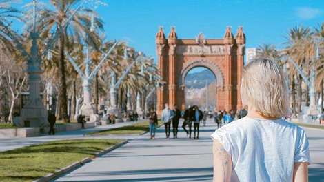 Ein Mädchen steht vor dem Arc de triomphe in Barcelona.