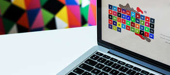 Bachelor Mediendesign Ausschnitt eines Notebooks. Links im Hintergrund hängt ein Bild, bestehend aus diversen bunten geometrischen Formen.