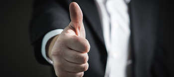 Bachelor Sicherheitsmanagement Ausschnitt einer Person, die ihren Daumen nach oben zeigt. Die Person trägt einen Anzug.