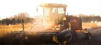 Studium Agrartechnik Eine Erntemachine erntet ein Feld in der Abenddämmerung.