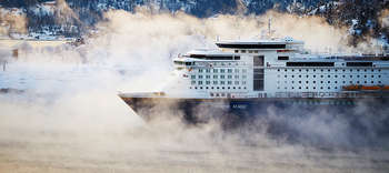 Bachelor Nautik Zu sehen ist der vordere Teil eines großen Schiffes, der von der Seite fotografiert wurde. Das Schiff trägt die Aufschrift: COLOR MAGIC. Umgeben ist das Schiff von eisernen Landschaft, aus dem Wasser steigt Nebel auf. Im Hintegrund ist ein von Schnee bedeckter Wald erkennbar.