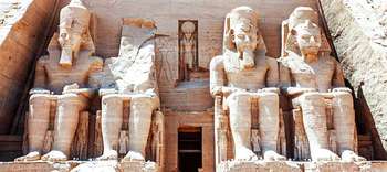 Ägyptologie Auf dem Bild befinden sich vier in Stein geschnitzte Statuen von Pharaonen. Diese befinden sich nebeneinander auf Thronen sitzend. Der Oberkörper der Statue in der mitte links ist dabei zerstört.