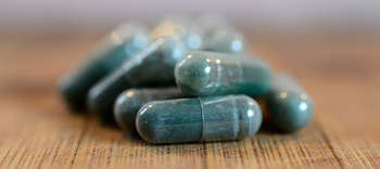 Bachelor Pharmazie Nahaufnahme von Kapsel-Tabletten auf hölzernem Untergrund.