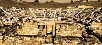 Archäologie Das Bild zeigt Überreste eines Amphitheaters. Die Sitzplätze sind gut erkennbar und das Bild ist in einem gelblichen Ton gehalten.