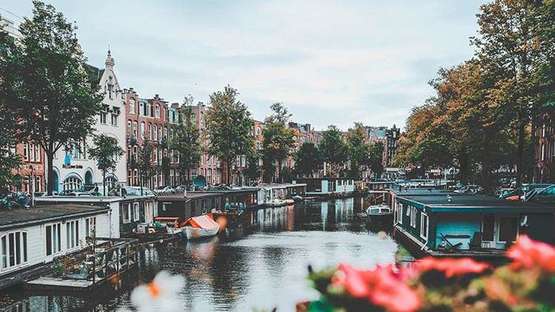Ausblick auf eine Gracht in Amsterdam. Auf dem Wasser viele Hausboote.