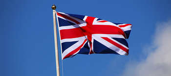 Bachelor Englisch Das Bild zeigt die englische Flagge hinter blauem Himmel im Wind wehen.