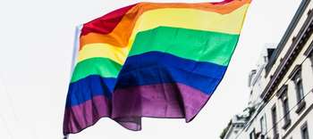 Bachelor Sozialrecht Ausschnitt einer in die Luft gehobenen Regenbogenfahne.