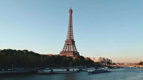 Ein befahrener Kanal in Paris, im Hintergrund der Eiffelturm. 