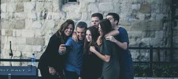 Bachelor Sozialwissenschaften Eine Personengruppe, bestehend aus drei Männern und drei Frauen, macht vor einer rustikal aussenden Mauer ein Selfie mit einem Handy.