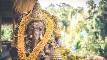Top 10 Gründe, um im Ausland zu studieren Abbildung einer Statue der Hindu-Gottheit Ganesha. Im Hintergrund eine Kulisse aus Pflanzen und Palmen durch die Sonnenstrahlen scheinen.