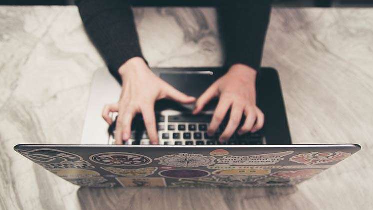 Bachelor-Studiengänge ohne Zulassungsbeschränkung Zulassungsfreie Studiengänge Jemand schreibt auf einem mit Stickern übersäten Laptop.
