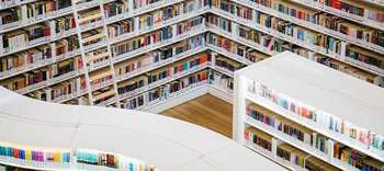 Bachelor Archiv Zu sehen ist der Ausschnitt einer modernen, großen und gut gefüllten Bibliothek. Die Regale sind allesamt in weiß gehalten.