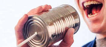 Bachelor Logopädie Ausschnitt des Mundes einer Person, die in ein Schnurtelefon ruft.