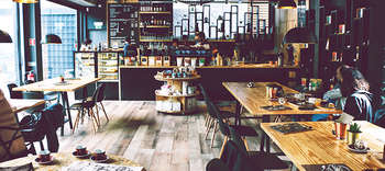 Bachelor Gastronomie Ein modernes und gemütlich wirkendes Lokal. Die Einrichtung mit zahlreichen Holzemelementen sowie dunklen Wänden.