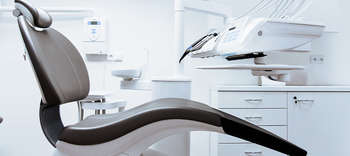 Bachelor Zahnmedizin Aufnahme eines modernen und steril wirkenden Behandlungsraumes beim Zahnarzt. Im Mittelpunkt des Bildes die Zahnarztliege.