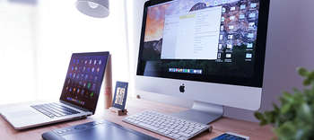 Bachelor Medienmanagement Ausschnitt eines Schreibtisches. Auf diesem befindet sich ein Computerbildschirm, ein Laptop sowie mehrere Pflanzen und Dekorationsartikel.