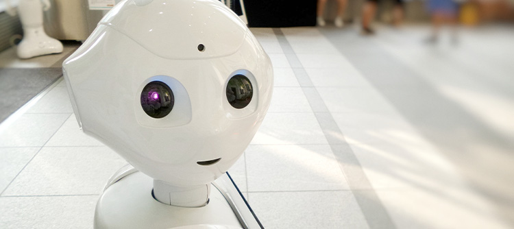 Bachelor Künstliche Intelligenz Zu sehen ist der Kopf eines Roboters. Der Roboter hat eine glänzende weiße Farbe, große Augen und der Mund formt sich zu einem Lächeln.