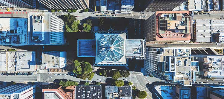 Bachelor Raumplanung Eine Großstadt aus der Vogelperspektive fotografiert. Erkennbar sind viele hohe Gebäude, welche relativ eng einander gebaut worden sind. Zwischen einzelnen Gebäuden befinden sich Bäume.