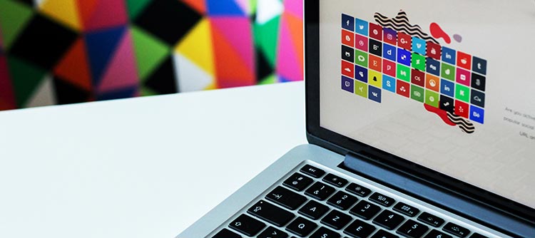Bachelor Mediendesign Ausschnitt eines Notebooks. Links im Hintergrund hängt ein Bild, bestehend aus diversen bunten geometrischen Formen.
