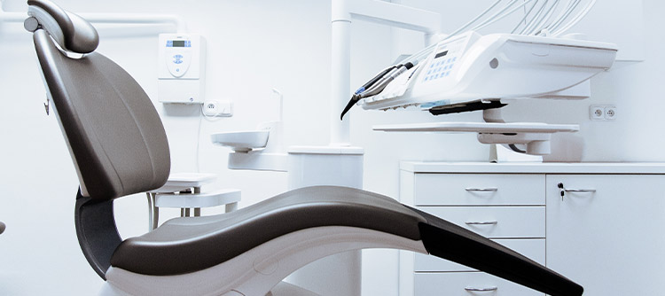 Bachelor Zahnmedizin Aufnahme eines modernen und steril wirkenden Behandlungsraumes beim Zahnarzt. Im Mittelpunkt des Bildes die Zahnarztliege.