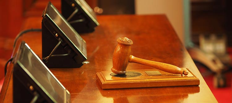 Bachelor Strafrecht Ausschnitt des Holztisches eines Richters. Im Fokus des Bildes der Richterhammer.