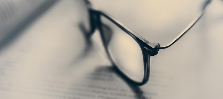 Rechtswissenschaften Das Bild zeigt eine Brille, die auf einem Buch abgelegt ist.