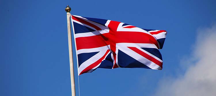 Bachelor Englisch Das Bild zeigt die englische Flagge hinter blauem Himmel im Wind wehen.