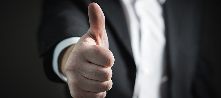 Bachelor Sicherheitsmanagement Ausschnitt einer Person, die ihren Daumen nach oben zeigt. Die Person trägt einen Anzug.